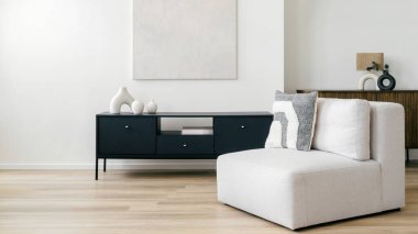 Beyaz kanepesi, siyah dolabı ve hafif ahşap döşemesi olan modern bir yaşam alanı. Oda büyük bir soyut tuval ve seramik vazolarla dekore edilmiştir..