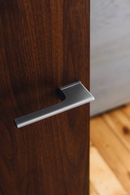Oturma odasındaki ahşap kapının parlak metal sapını kapat. Modern minimalizm. Çağdaş dairede iç tasarım unsurları kavramları