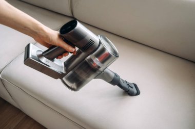 Bir insan küçük bir süpürge kullanarak koltuktaki lekeleri ve tozu çıkartıyor. Işık döşemelerine seçici odaklanma