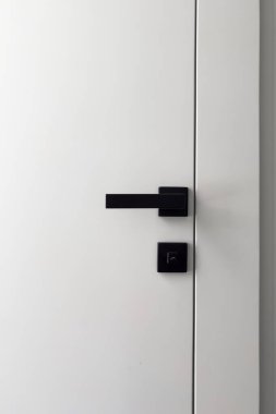 Bu modern iç kapı, çağdaş ev tasarımında minimalist estetik ve işlevselliği vurgulayan basit bir siyah sapı ve kilidi sergiliyor..