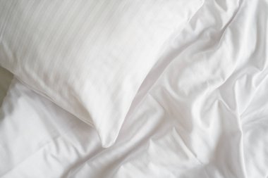 Beyaz yastıklı, köpük yastıklı, temiz ve temiz çarşaflı bir otel odası. Rahat bir uyku, rahat bir yatak odası, çamaşır günü konseptleri.