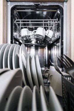 Modern bulaşık makinesinin içindeki beyaz tabak ve kâselere odaklan. Eko modu ve enerji verimli programı olan cihazlar. Mutfak için ev aletleri. Temiz tabaklar, yakın çekim, dikey çekim.