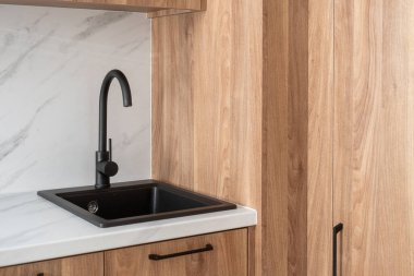 Çağdaş bir mutfak modern su musluğu olan şık siyah bir lavabo mermer tezgahlara inşa edilmiş, doğal ahşap dolaplara karşı fotokopi alanı olan