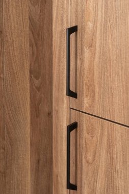 Minimalist siyah saplı tahta dolabın dikey görüntüsü, çağdaş bir alanda ahşabın doğal yapısını vurguluyor. Yatak odasında ya da oturma odasında gardırop