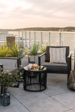 Modern apartman ve deniz manzaralı bir ev. Çatı terası, siyah sandalyesi, cam tepeli masası ve saksı bitkileri. Otelde ya da özel mülkte çatı terası, dikey çekim