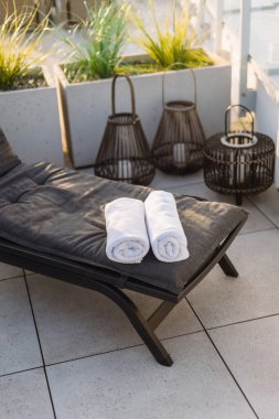 İki beyaz havlu sarılıp verandadaki koyu gri şezlonga konur. Otelin çatı katındaki terasta rahat bir sandalye. Fenerlerdeki mumlara karşı iskemle.