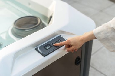 Kadın konfor sıcaklığını seçer ve küvetin ışığını açar. Kontrol panelinde kadın el düğmesi, jakuzide hidroterapi jeti ve ısıtma suyu.