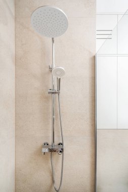 Minimalist bir banyo tasarımında başlık ve el yapımı duşun dikey çekimi. Evdeki minimalist tesisat ile çağdaş iç mimari