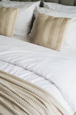 İki uyumlu dekoratif yastıklı, yumuşak, beyaz battaniyeli, köpük yastıklı. Taze beyaz yatak odası düzenlemesi yapıyor. Sağlıklı uyku kavramı, hafta sonları evde dinlenmek.