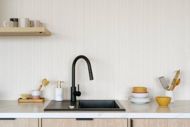 Mutfak tezgahında lavabo, ev malzemeleri, bulaşık deterjanı ve çevre dostu bambu fırçası var.