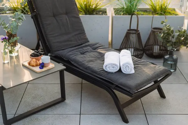 Çatı terasında havuzu olan beyaz pamuklu siyah şezlong. Terasta yiyecek ve içeceklerle yan masada. Yaz tatili, dinlenme ve rahatlama kavramları.