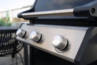 Metalik saplı gaz ızgarasının kontrol düğmelerini yakından çek. Verandada et ve sebze kızartmak için modern barbekü ekipmanları, seçici odaklanma