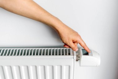 Bir el beyaz elektrikli radyatörün kontrolünü ayarlar. Soğuk hava koşullarında, sıcak bir yaşam alanı için uygun sıcaklığı ayarlar..