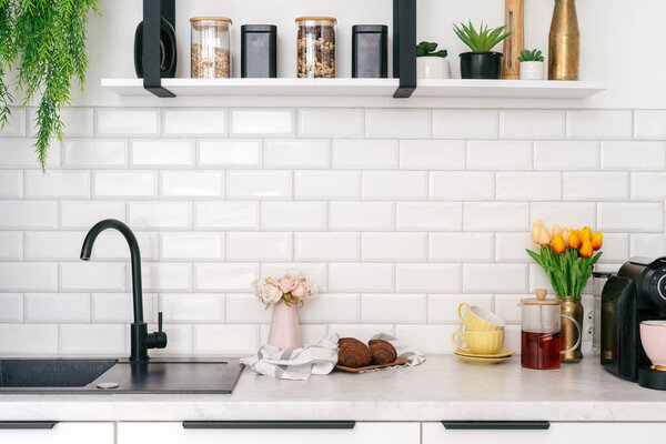 Стильный кухонный стол с раковиной и краном рядом со свежими цветами, хлебобулочными изделиями и ярким декором, создавая уютную атмосферу. Стол для приготовления еды и напитков
