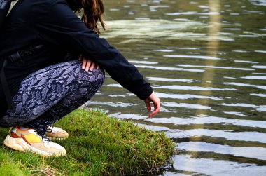 Gölün kıyısında tanınmayan genç bir kadın. Saf ve kristal suya dokunduğunda eli ıslanır. Dinleniyor ve doğaya hayran..