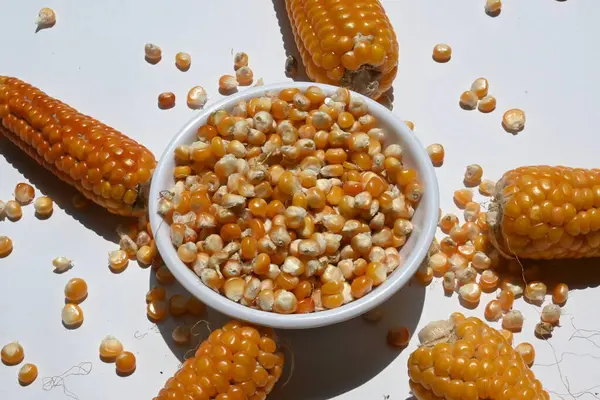 Dry corn seeds in bowl isolated on white background. Its other names maize, Zea mays, sugar or pole corn. This is vegetarian staple food. It is a source of many vitamins. Unpopped popcorn.