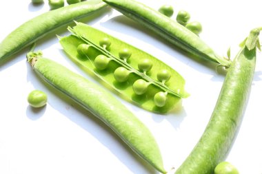 Beyaz arka planda taze yeşil bezelye. İçinde bir sürü vitamin ve mineral var. Bezelye genellikle küçük bir kürenin tohumu olur. Dünyanın en popüler sebzesi.. 