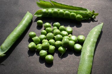 Siyah arka planda taze bezelye. İçinde bir sürü vitamin ve mineral var. Bezelye genellikle küçük bir kürenin tohumu olur. Dünyanın en popüler sebzesi.. 