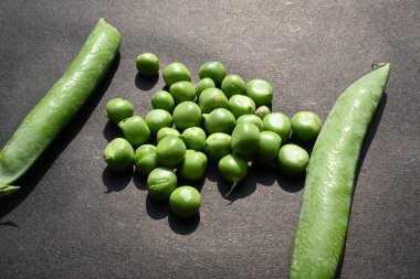 Siyah arka planda taze bezelye. İçinde bir sürü vitamin ve mineral var. Bezelye genellikle küçük bir kürenin tohumu olur. Dünyanın en popüler sebzesi.. 