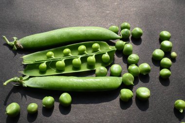 Siyah arka planda taze bezelye. İçinde bir sürü vitamin ve mineral var. Bezelye genellikle küçük bir kürenin tohumu olur. Dünyanın en popüler sebzesi.. 