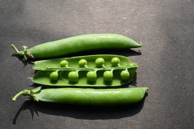 Siyah arka planda taze bezelye. İçinde bir sürü vitamin ve mineral var. Bezelye genellikle küçük bir kürenin tohumu olur. Dünyanın en popüler sebzesi.. 