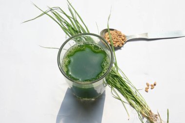 Beyaz arka planda buğday çimi suyu. Yeşil filizlenmiş buğday tanelerinin çimlerinden sağlıklı organik yeşil detoks suyu. Sağlıklı bir içki. Genç buğday ve buğday suyundan yeşil yapraklar.