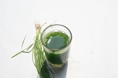 Beyaz arka planda buğday çimi suyu. Yeşil filizlenmiş buğday tanelerinin çimlerinden sağlıklı organik yeşil detoks suyu. Sağlıklı bir içki. Genç buğday ve buğday suyundan yeşil yapraklar.