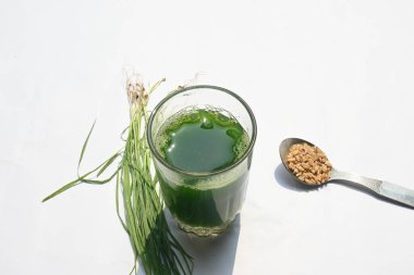 Beyaz arka planda buğday çimi suyu. Yeşil filizlenmiş buğday tanelerinin çimlerinden sağlıklı organik yeşil detoks suyu. Sağlıklı bir içki. Genç buğday ve buğday suyundan yeşil yapraklar.