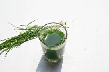 Beyaz arka planda buğday çimi suyu. Yeşil filizlenmiş buğday tanelerinin çimlerinden sağlıklı organik yeşil detoks suyu. Sağlıklı bir içki. Genç buğday ve buğday suyundan yeşil yapraklar.