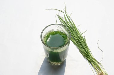 Beyaz arka planda buğday çimi suyu. Yeşil filizlenmiş buğday tanelerinin çimlerinden sağlıklı organik yeşil detoks suyu. Sağlıklı bir içki. Genç buğday ve buğday suyundan yeşil yapraklar.