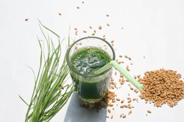 Beyaz arka planda buğday çimi suyu. Yeşil filizlenmiş buğday tanelerinin çimlerinden sağlıklı organik yeşil detoks suyu. Sağlıklı bir içki. Genç buğday ve buğday suyundan yeşil yapraklar.