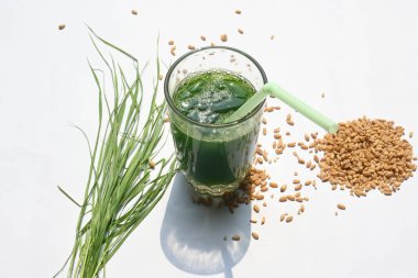 Beyaz arka planda buğday çimi suyu. Yeşil filizlenmiş buğday tanelerinin çimlerinden sağlıklı organik yeşil detoks suyu. Sağlıklı bir içki. Genç buğday ve buğday suyundan yeşil yapraklar.
