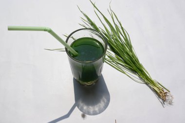 Beyaz arka planda buğday çimi suyu. Yeşil filizlenmiş buğday tanelerinin çimlerinden sağlıklı organik yeşil detoks suyu. Sağlıklı bir içki. Genç buğday ve buğday suyundan yeşil yapraklar.
