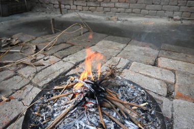 Yanan odun ateşi. Yangın üflenerek alevlendiriliyor. Tahta ateş. Hindistan 'ın kırsal bölgesi.