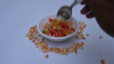 Haşlanmış mısır Chaat. Hint usulü mısır salatası. Tatlı, baharatlı ve keskin. Chaat masala, kavrulmuş kimyon tozu, kırmızı biber tozu, kişniş yaprağı, soğan ve domatesle karıştırılır. Hint yemekleri..