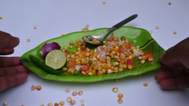 Haşlanmış mısır Chaat. Hint usulü mısır salatası. Tatlı, baharatlı ve keskin. Chaat masala, kavrulmuş kimyon tozu, kırmızı biber tozu, kişniş yaprağı, soğan ve domatesle karıştırılır. Hint yemekleri..