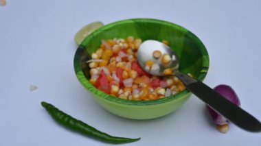 Haşlanmış mısır Chaat. Hint usulü mısır salatası. Tatlı, baharatlı ve keskin. Chaat masala, kavrulmuş kimyon tozu, kırmızı biber tozu, kişniş yaprağı, soğan ve domatesle karıştırılır. Hint yemekleri..