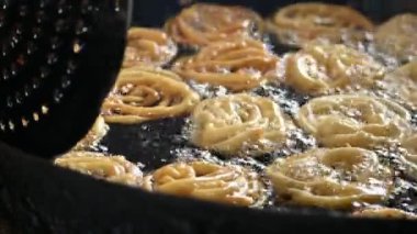 Jalebi yapımı. Hindistan 'ın alt kıtasında popüler bir atıştırmalık. Birçok isim var; jilebi, jilipi, zulbia, mushabak, zlabia ve zalabia. Maida un ve şeker şurubu tarafından yapıldı..