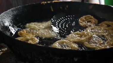 Jalebi yapımı. Hindistan 'ın alt kıtasında popüler bir atıştırmalık. Birçok isim var; jilebi, jilipi, zulbia, mushabak, zlabia ve zalabia. Maida un hamuru ve şeker şurubu tarafından yapılıyor. Yavaş çekim videosu. 