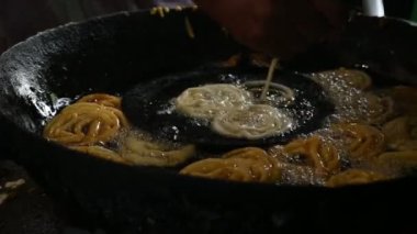 Jalebi yapımı. Hindistan 'ın alt kıtasında popüler bir atıştırmalık. Birçok isim var; jilebi, jilipi, zulbia, mushabak, zlabia ve zalabia. Maida un hamuru ve şeker şurubu tarafından yapılıyor. Yavaş çekim videosu. 