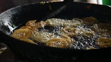 Jalebi yapımı. Hindistan 'ın alt kıtasında popüler bir atıştırmalık. Birçok isim var; jilebi, jilipi, zulbia, mushabak, zlabia ve zalabia. Maida un hamuru ve şeker şurubu tarafından yapılıyor. Yavaş çekim videosu. 