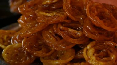Jalebi tatlıları. Hindistan 'ın alt kıtasında popüler bir atıştırmalık. Birçok isim var; jilebi, jilipi, zulbia, mushabak, zlabia ve zalabia. Maida un hamuru ve şeker şurubu tarafından yapılıyor. Yavaş çekim videosu. 