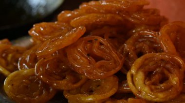 Jalebi tatlıları. Hindistan 'ın alt kıtasında popüler bir atıştırmalık. Birçok isim var; jilebi, jilipi, zulbia, mushabak, zlabia ve zalabia. Maida un hamuru ve şeker şurubu tarafından yapılıyor. Yavaş çekim videosu. 