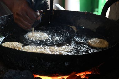 Jalebi yapımı. Hindistan 'ın alt kıtasında popüler bir atıştırmalık. Birçok isim var; jilebi, jilipi, zulbia, mushabak, zlabia ve zalabia. Maida un ve şeker şurubu tarafından yapıldı..