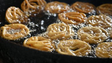 Jalebi yapımı. Hindistan 'ın alt kıtasında popüler bir atıştırmalık. Birçok isim var; jilebi, jilipi, zulbia, mushabak, zlabia ve zalabia. Maida un ve şeker şurubu tarafından yapıldı..