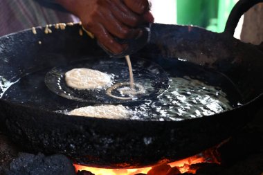 Jalebi yapımı. Hindistan 'ın alt kıtasında popüler bir atıştırmalık. Birçok isim var; jilebi, jilipi, zulbia, mushabak, zlabia ve zalabia. Maida un ve şeker şurubu tarafından yapıldı..