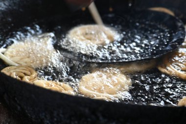 Jalebi yapımı. Hindistan 'ın alt kıtasında popüler bir atıştırmalık. Birçok isim var; jilebi, jilipi, zulbia, mushabak, zlabia ve zalabia. Maida un ve şeker şurubu tarafından yapıldı..