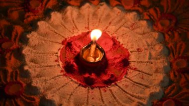 Canlı renklerde güzel rangoli tasarımı. Rangoli 'nin ortasına küçük, aydınlık bir diya ya da yağ lambası konur ve sıcak bir parıltı yayar. renkler şenlikli ve kutlama atmosferi.