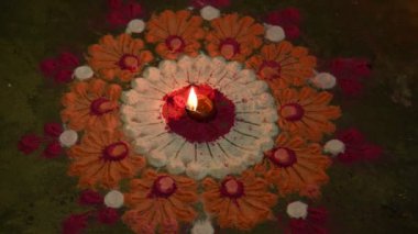 Canlı renklerde güzel rangoli tasarımı. Rangoli 'nin ortasına küçük, aydınlık bir diya ya da yağ lambası konur ve sıcak bir parıltı yayar. renkler şenlikli ve kutlama atmosferi.