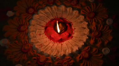 Canlı renklerde güzel rangoli tasarımı. Rangoli 'nin ortasına küçük, aydınlık bir diya ya da yağ lambası konur ve sıcak bir parıltı yayar. renkler şenlikli ve kutlamalı atmosfer. Yavaş çekim videosu. 